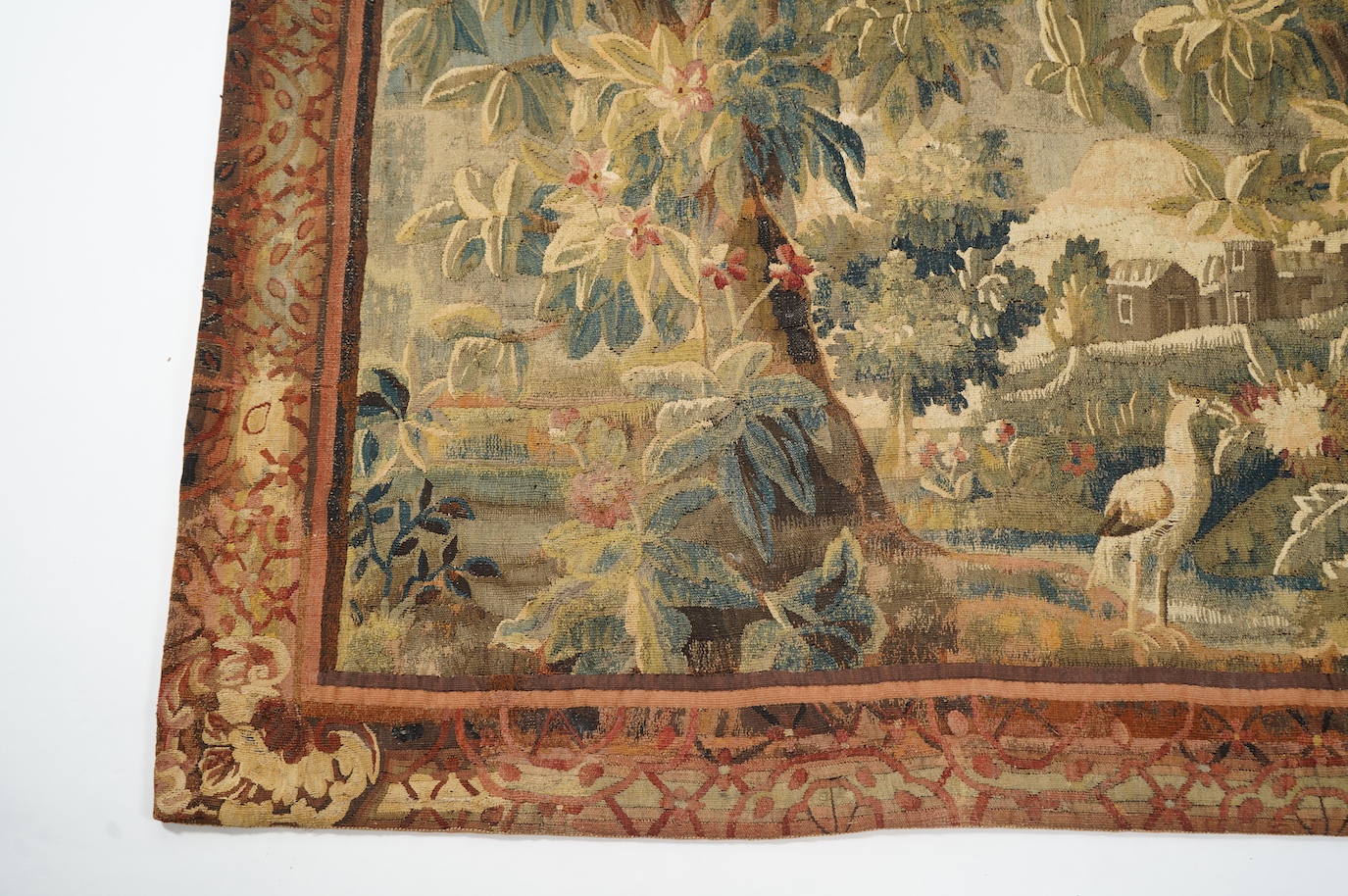 A mid to late 18th century French Aubusson tapestry of a bird, possibly a heron, within a tree lined verdure garden scene to a chateaux, with an ornate rust coloured contrasting tapestry border.201cm x 170 cm. Condition